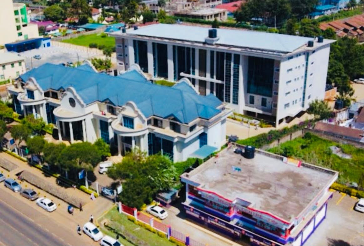 Aerial view of Tsavo, a modern institutional complex with white and blue buildings, landscaping and parked vehicles